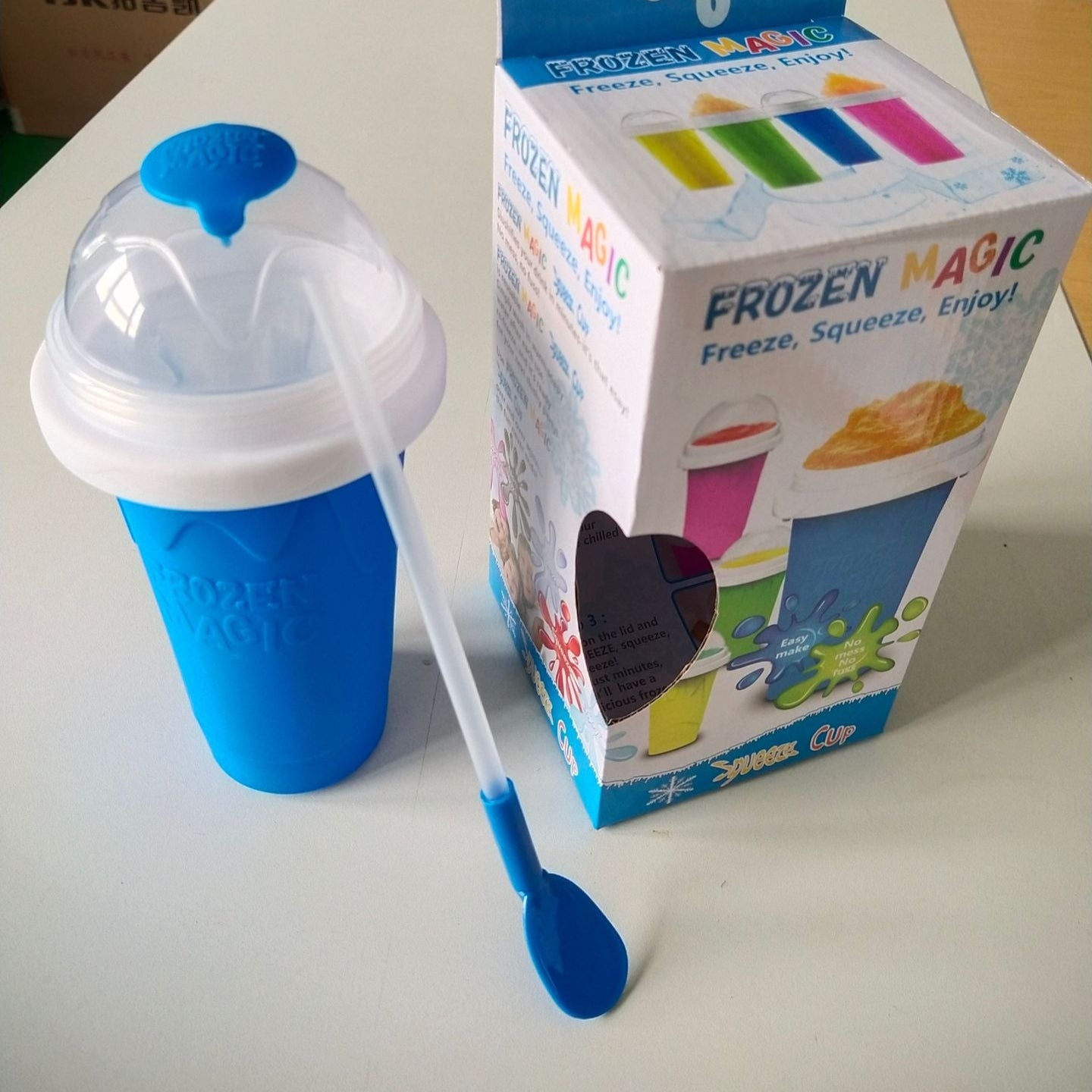 Blue Slushy Maker Cup with a spoon and packaging labeled 'Frozen Magic' on a white surface.