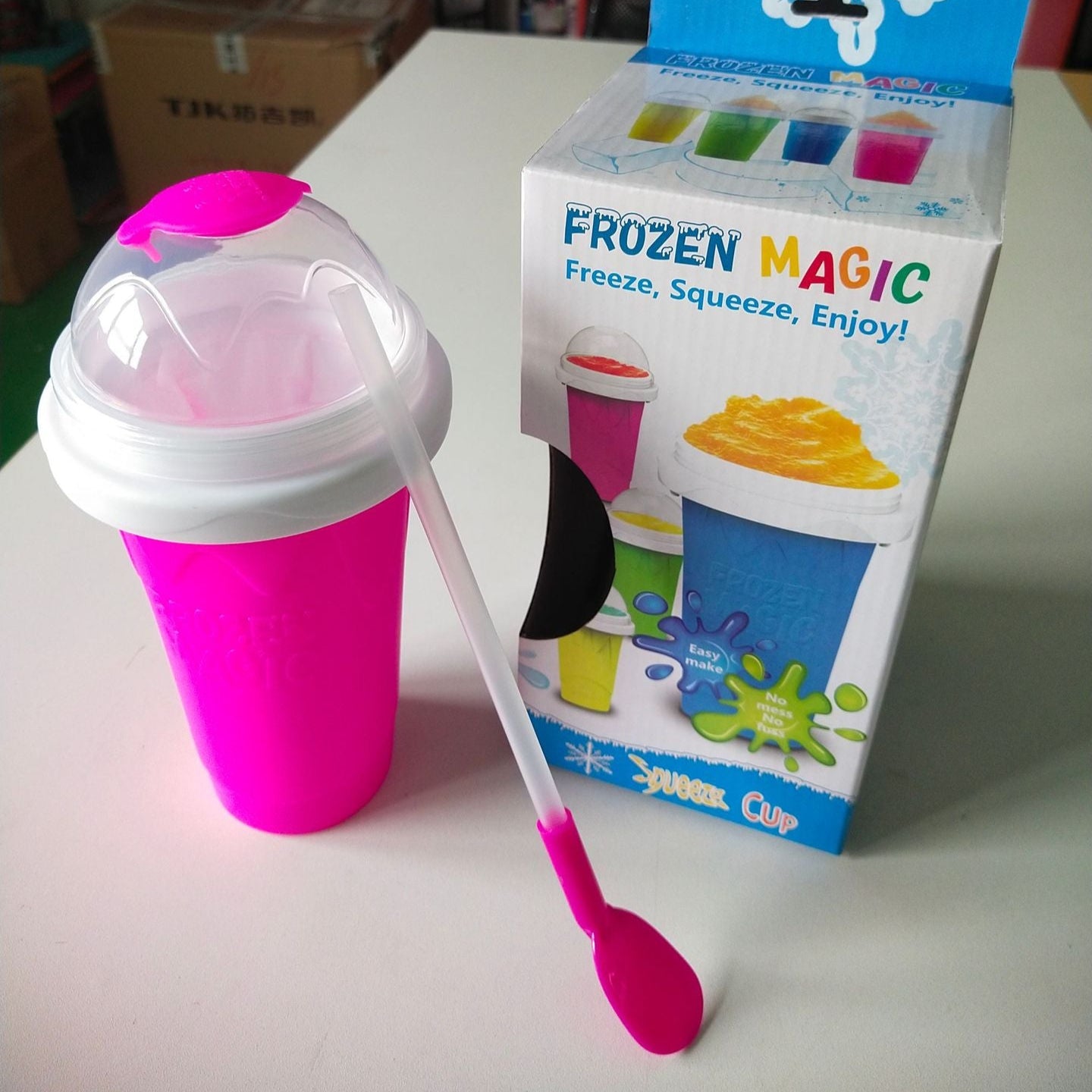 Pink ice cream cup with spoon and 'Frozen Magic' packaging on a white surface